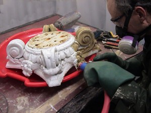 Heavy paint buildup on this carved wooden column capital is softened by steam and removed with careful scraping.